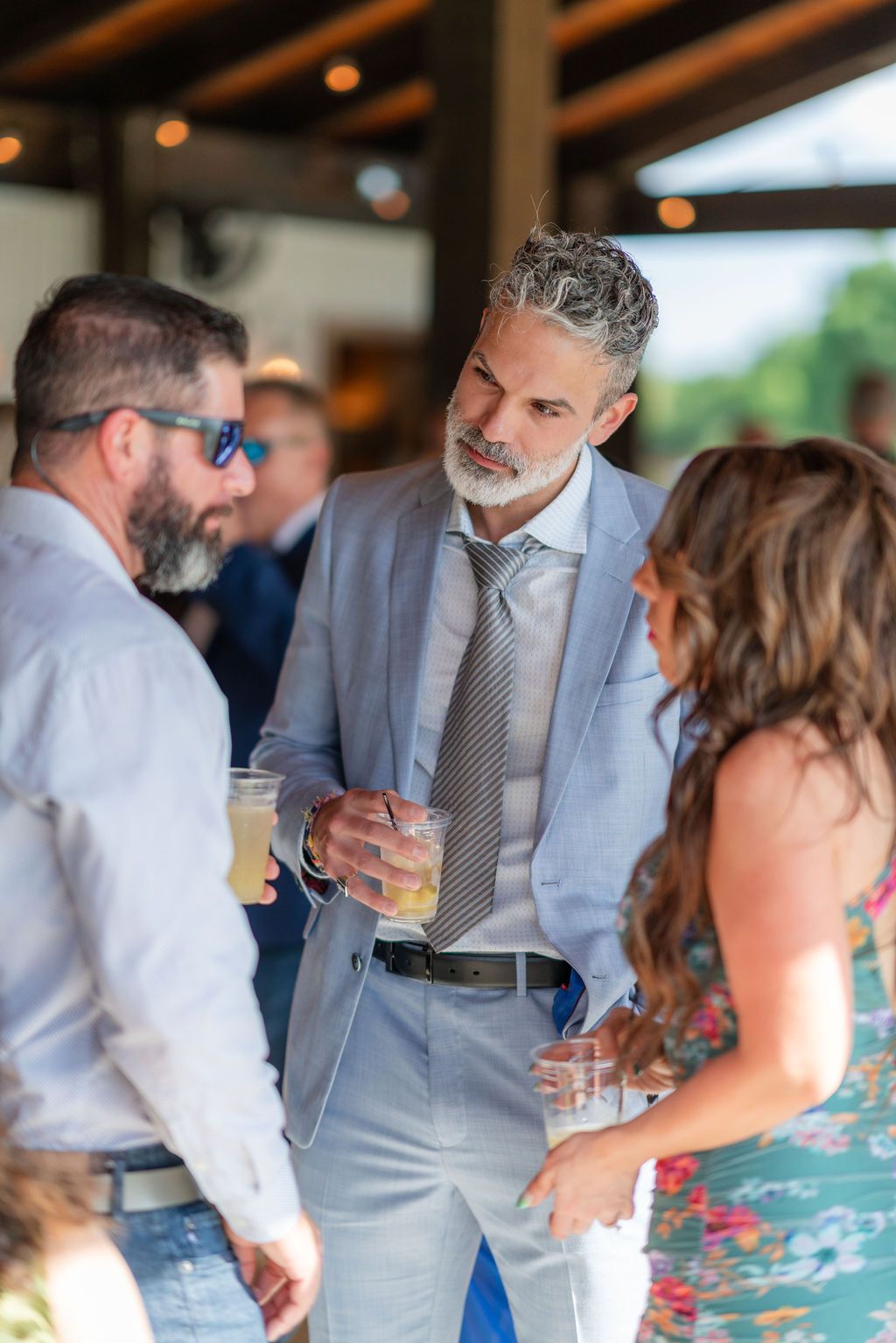 Guests talking with drinks during cocktail hour on the covered patio at a Rockin' H Ranch wedding in Palm City, FL