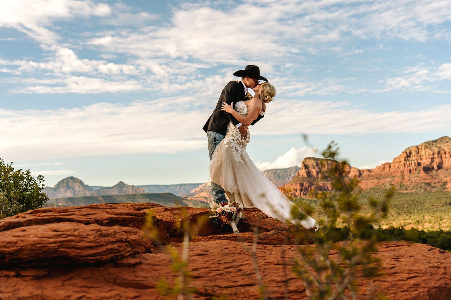 Bride and groom share a romantic moment at sunset in Sedona, Arizona, surrounded by red rocks and desert landscape.