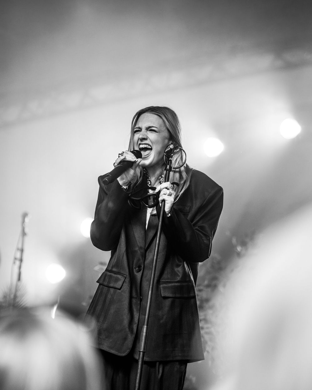 Black and white photo of a female singer performing passionately on stage with bright lights behind her.