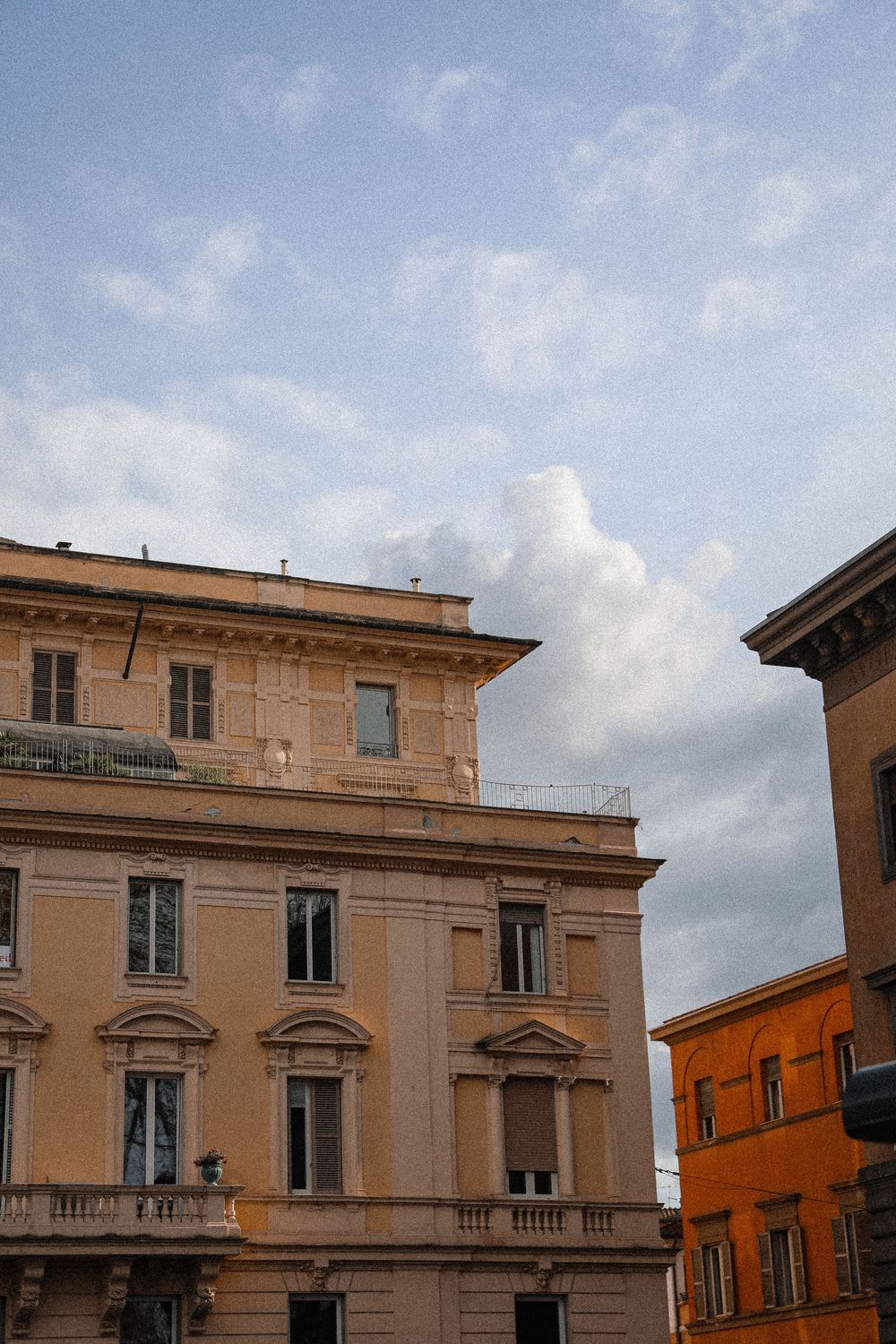 Classic Italian Renaissance buildings with ornate facades under a partly cloudy sky in Rome, Italy.