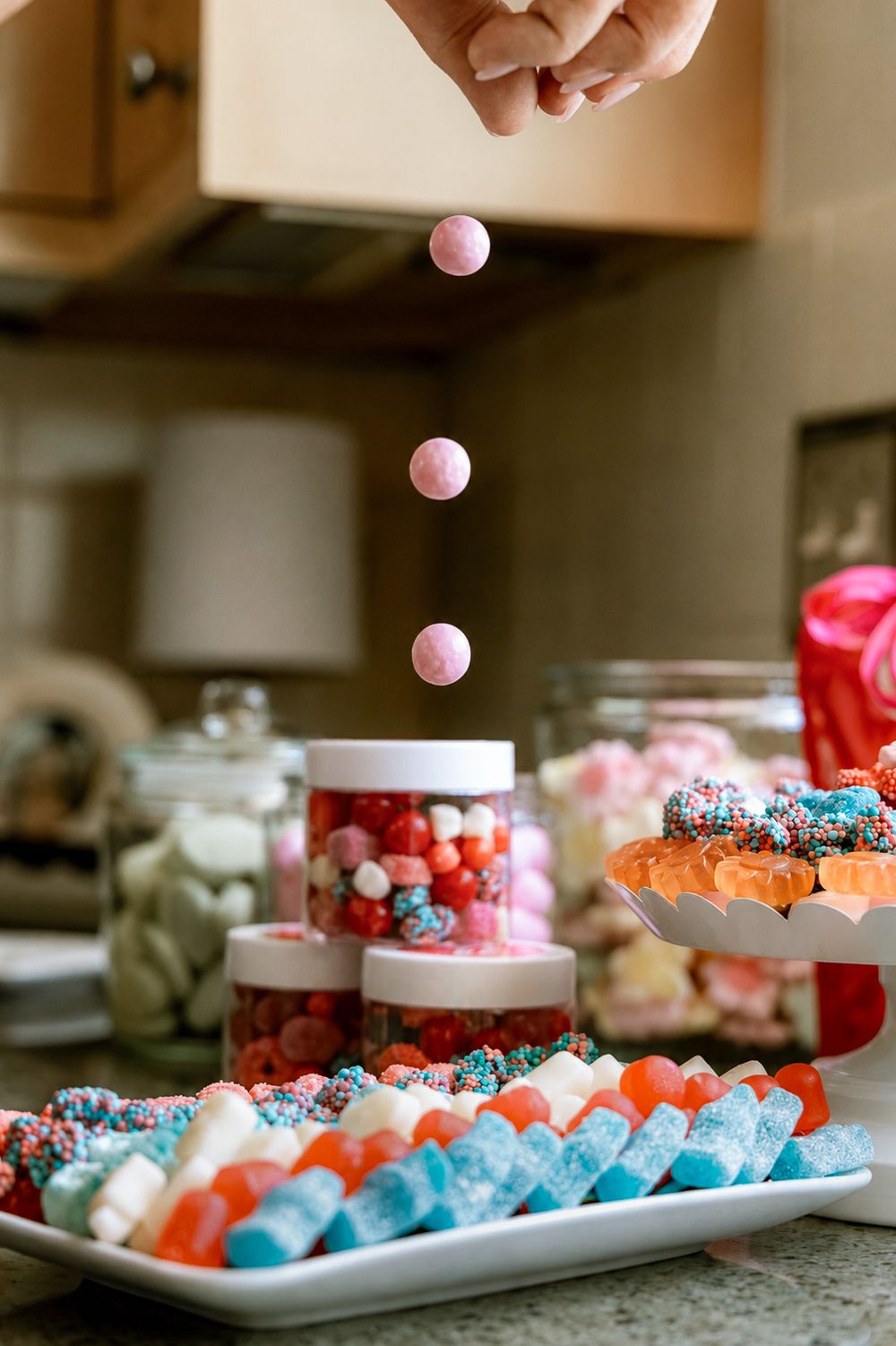 Colorful candy display with gummy bears, sprinkled chocolates, and jars of sweets on a kitchen counter.