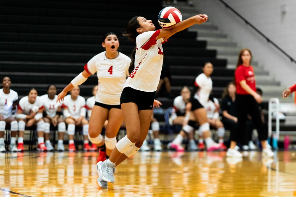 Female volleyball player diving to dig the ball during a competitive indoor match.