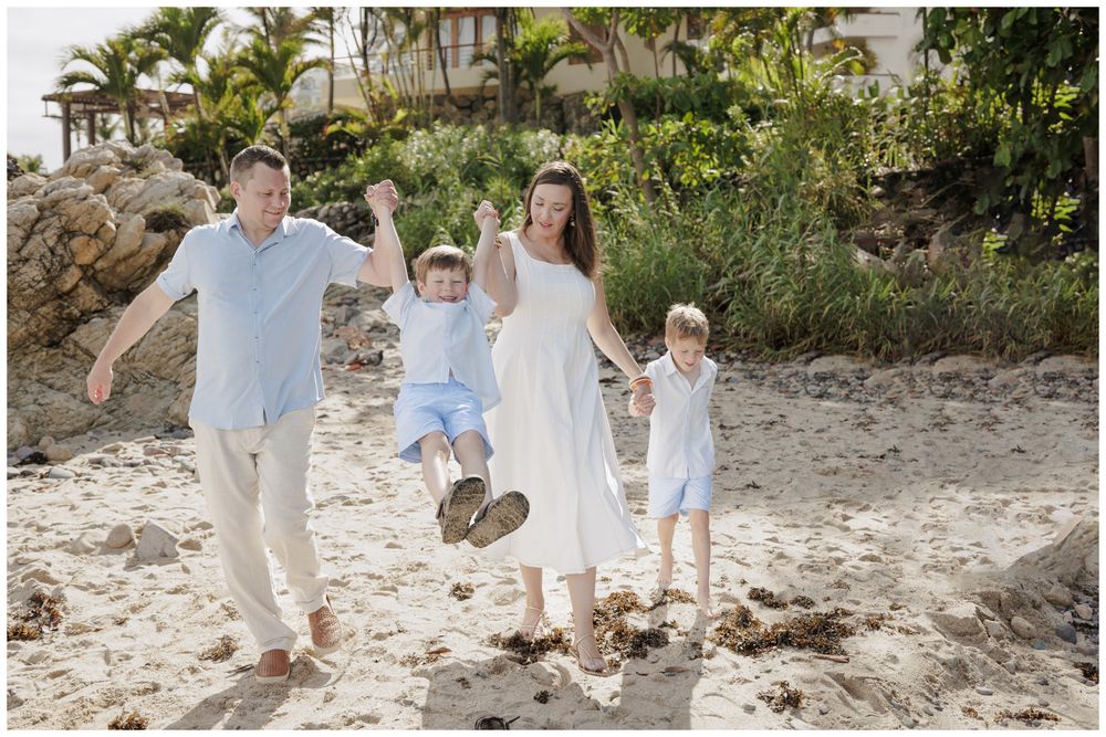 Family Beach Photos at Conchas Chinas Beach in Puerto Vallarta with parents playfully swinging their two sons.