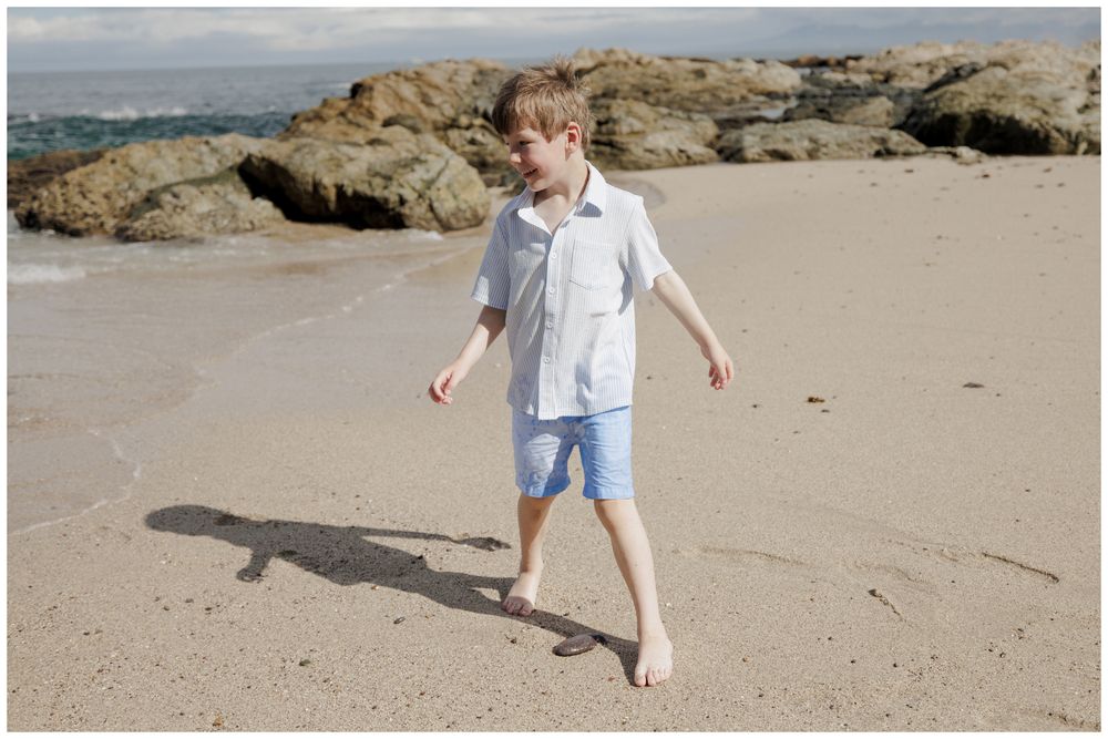 Family Vacation Photos at Conchas Chinas Beach in Puerto Vallarta featuring a young son walking barefoot along the sandy shoreline.