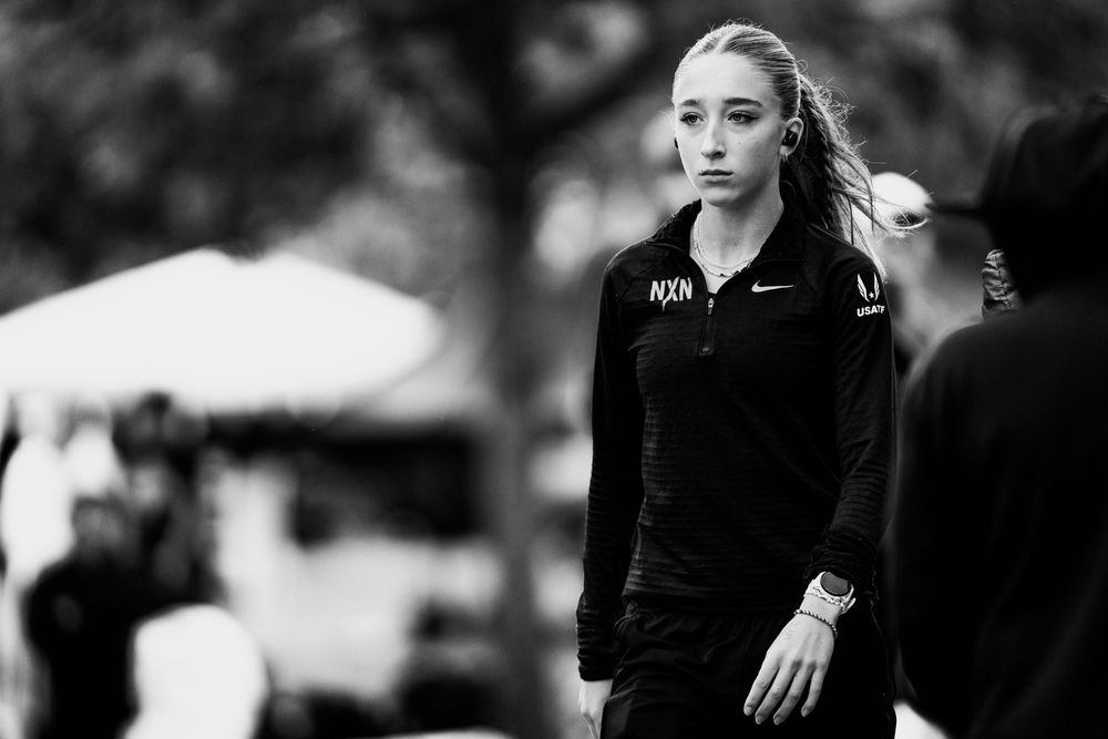 Black and white portrait of a focused female athlete in Nike NXN gear at a cross country event.