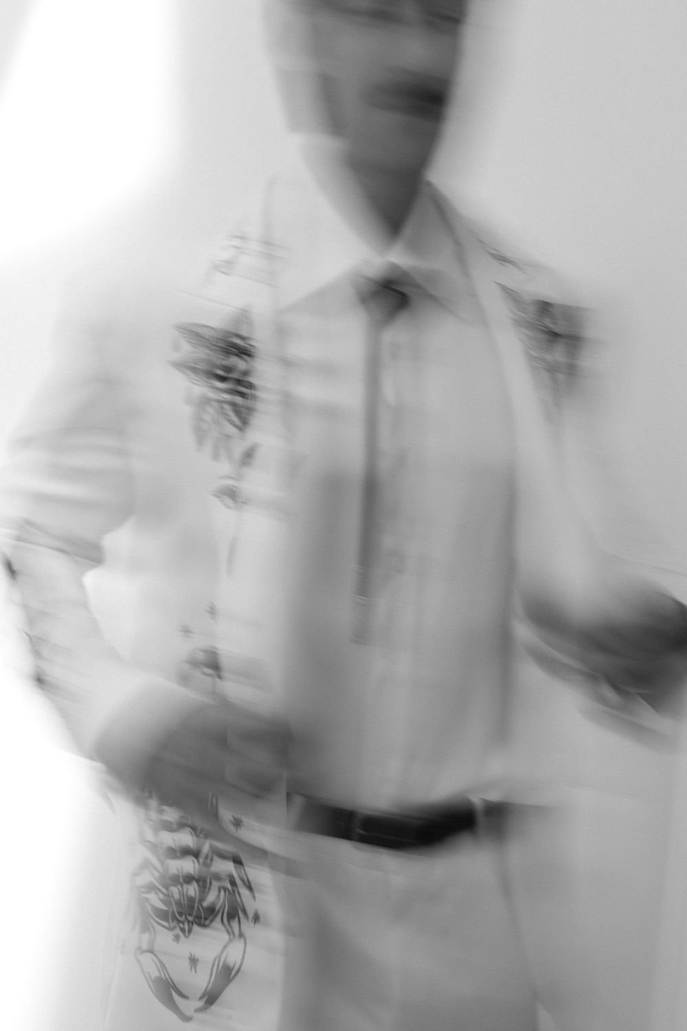 Blurred black and white motion photo of a man in dress shirt and tie, creating an artistic double exposure effect.