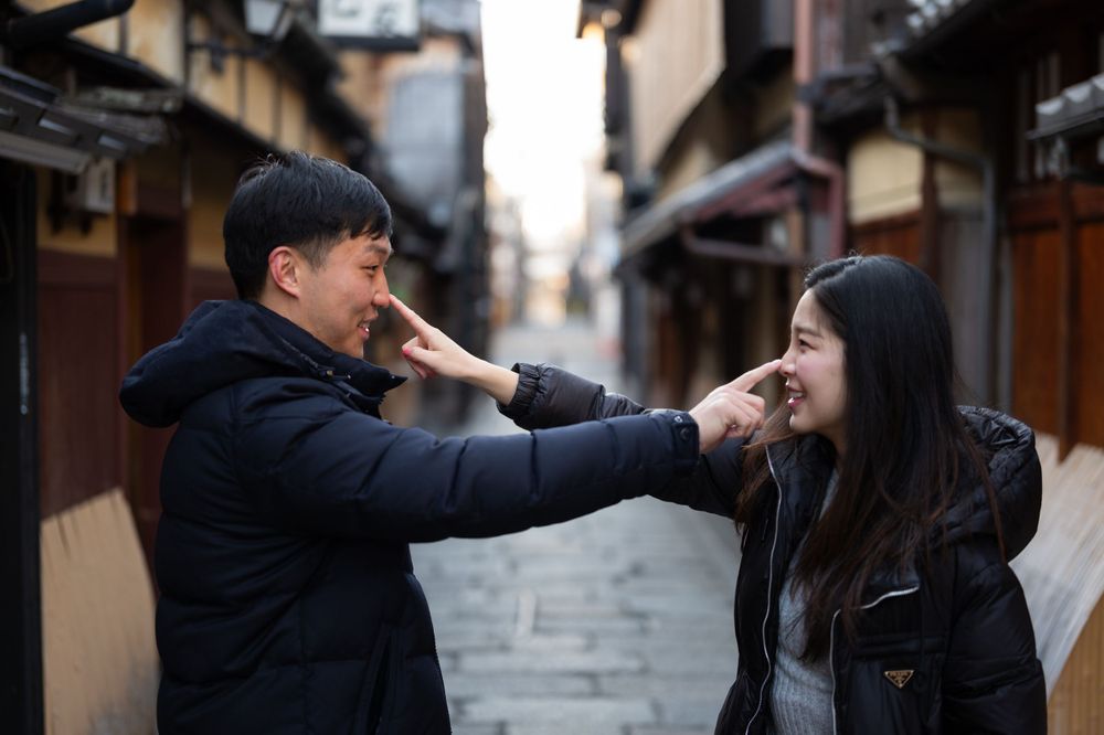 Playful Asian couple touching each other's noses on a traditional Japanese alleyway street.