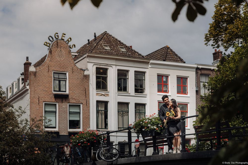 Couple embracing on a bridge in front of historic Dutch canal houses in Utrecht, Netherlands.