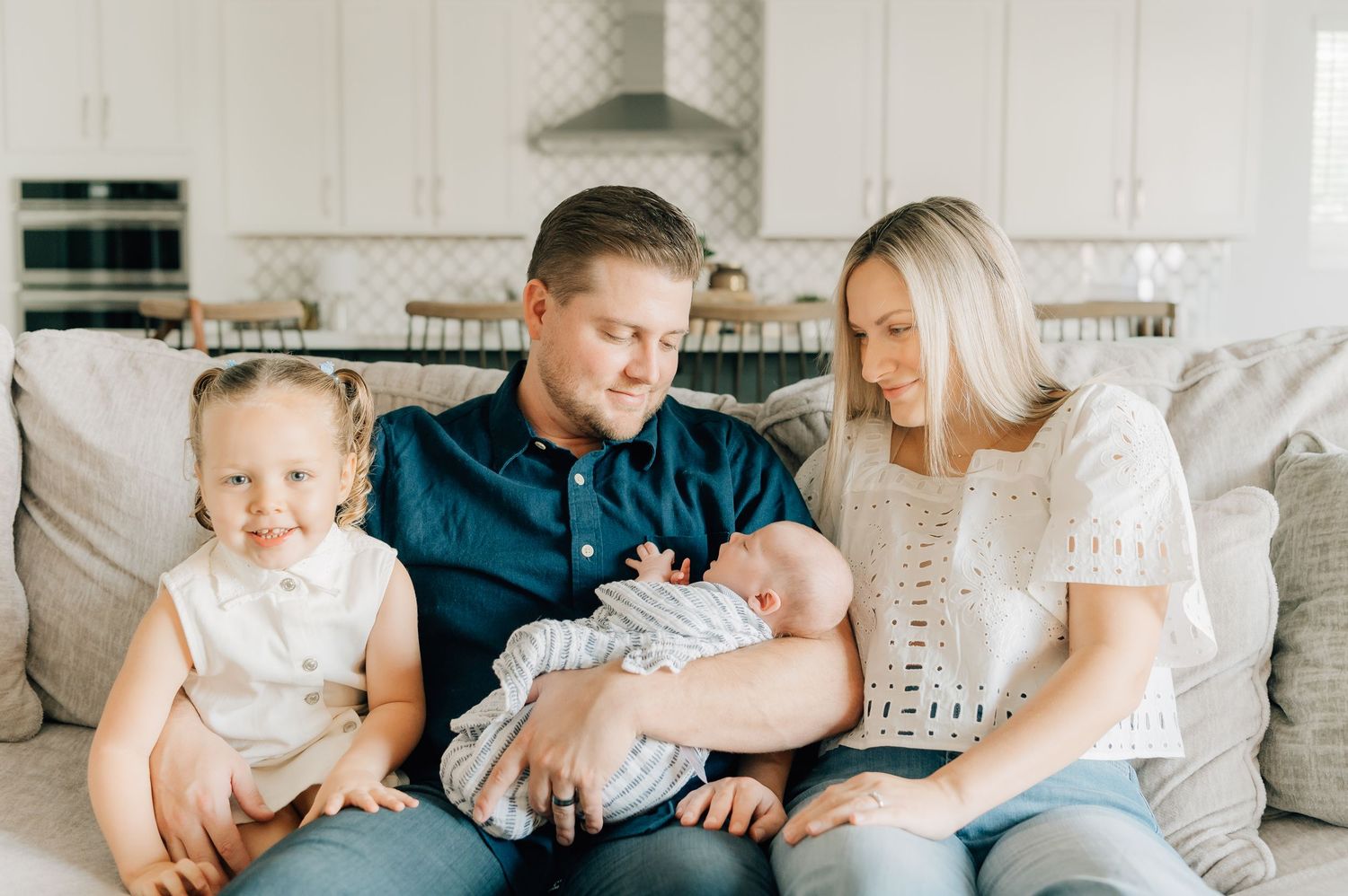 Lifestyle newborn photography in Peoria, Arizona with family snuggling their baby at home
