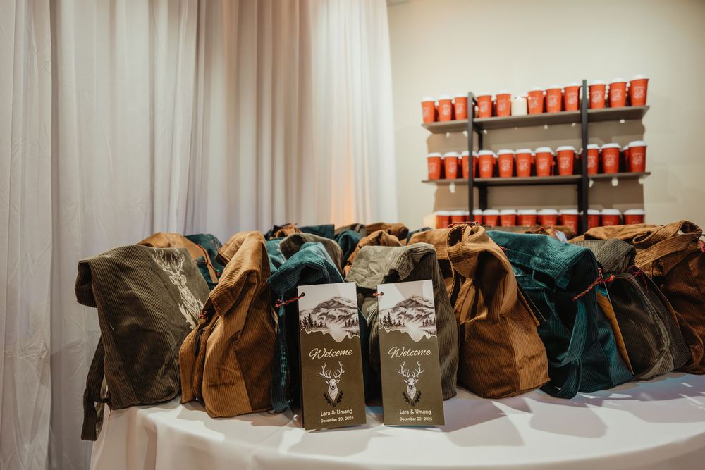 Rustic waxed canvas backpacks displayed on a table with welcome gift bags and red candles on a shelf.