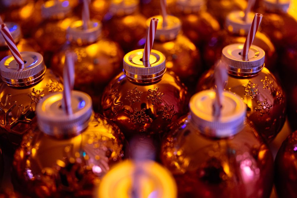 Rows of amber mason jar drinks with metal lids and straws glowing under warm golden light at an event.