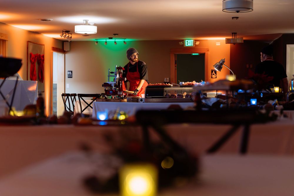 DJ performing at a dimly lit event venue with warm orange ambient lighting and equipment in the foreground.