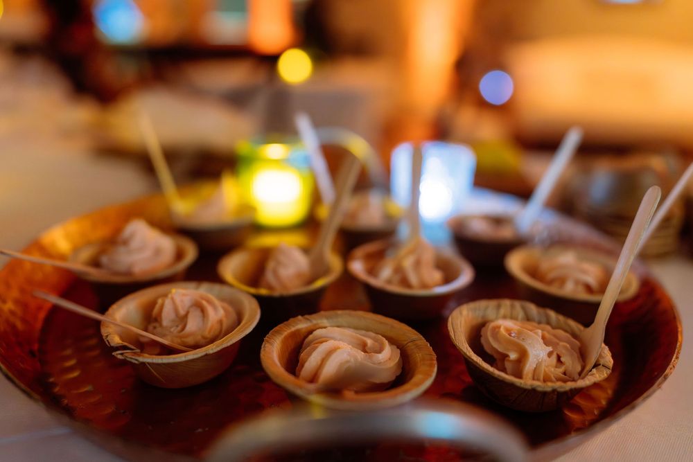 Small chocolate dessert cups with cream filling on a wooden tray, elegantly presented at a catered event.