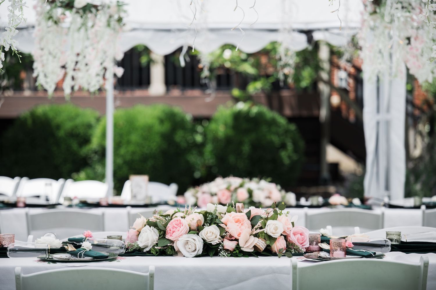Elegant wedding table centerpiece with pink and white roses arranged on a white tablecloth.