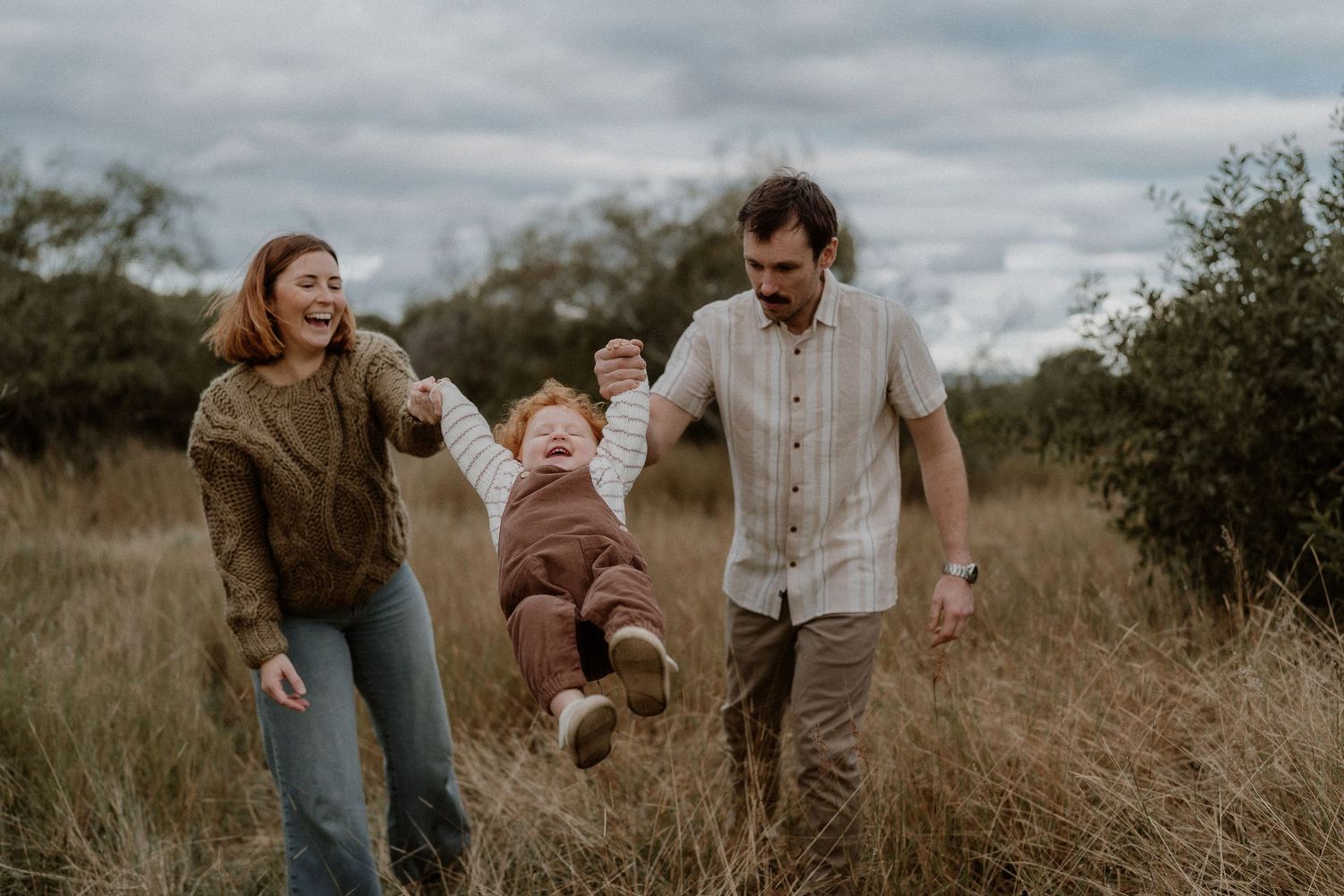 Family swinging their readheaded toddler in Picton NSW