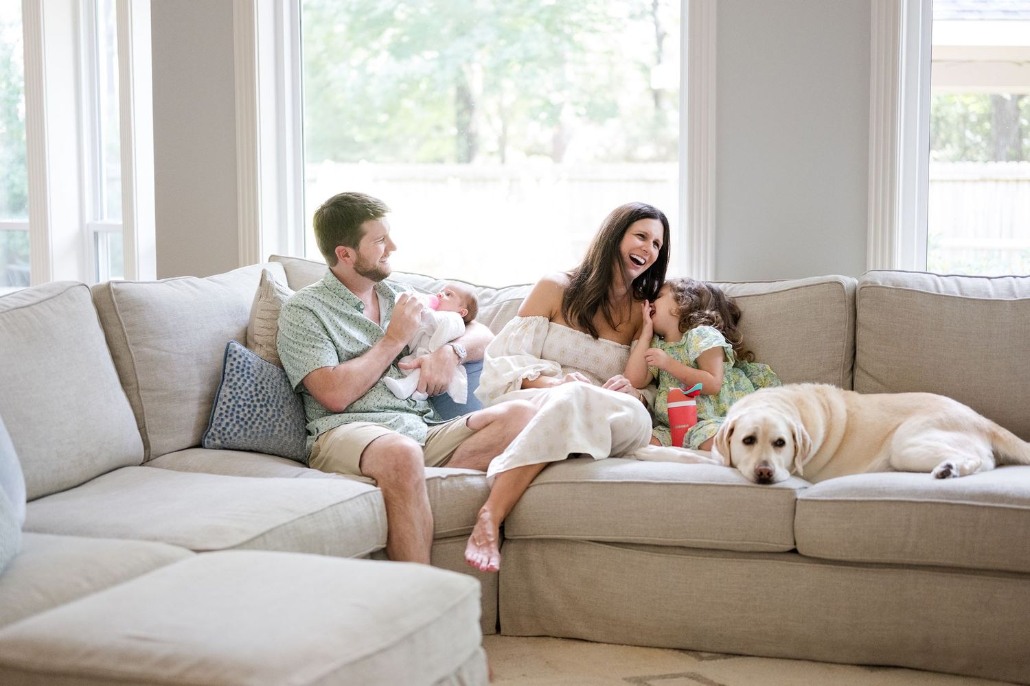 Parents and older sibling snuggling with their new baby at home