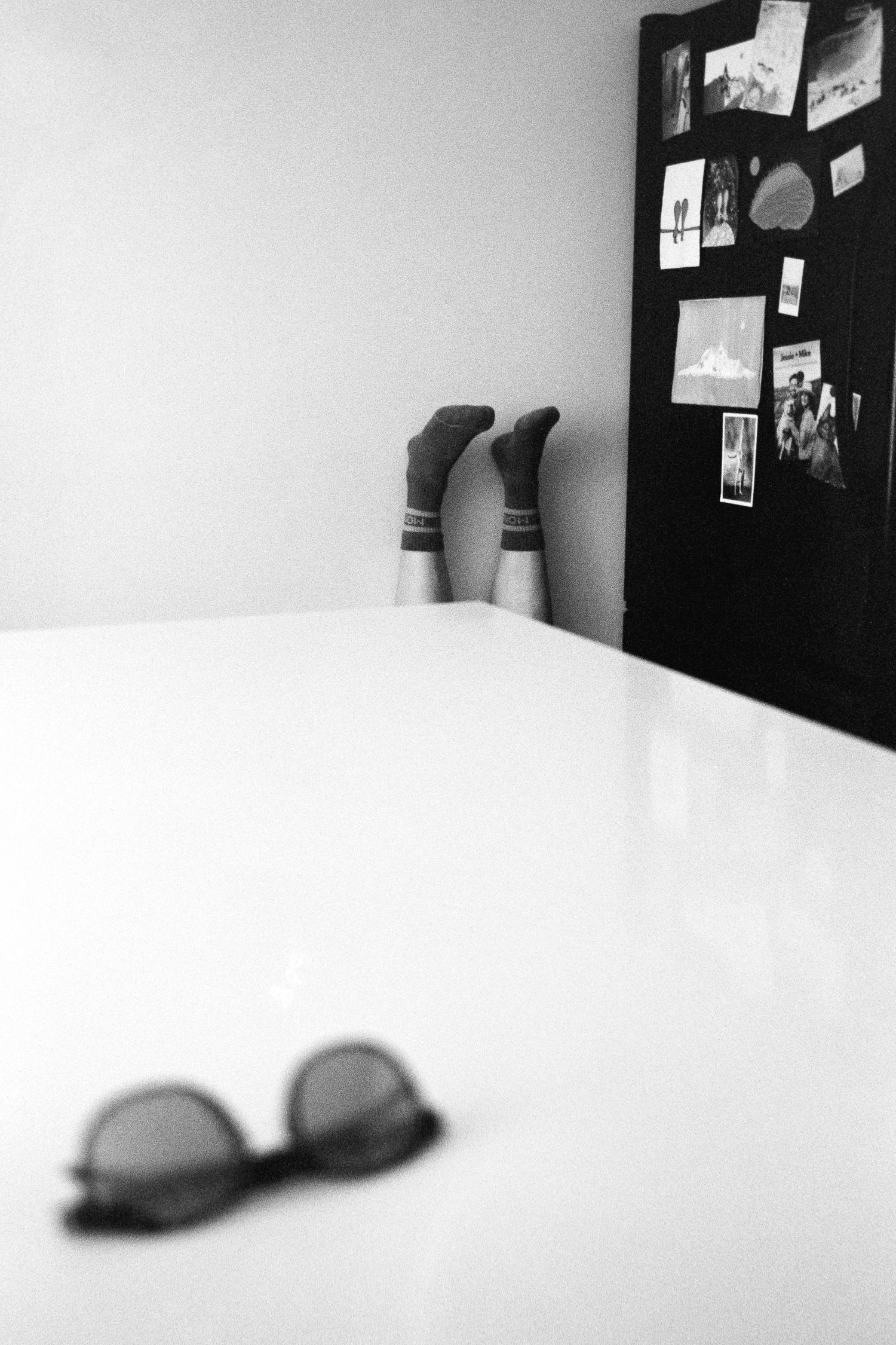 Black and white photo of socks and sunglasses with photos on a wall.