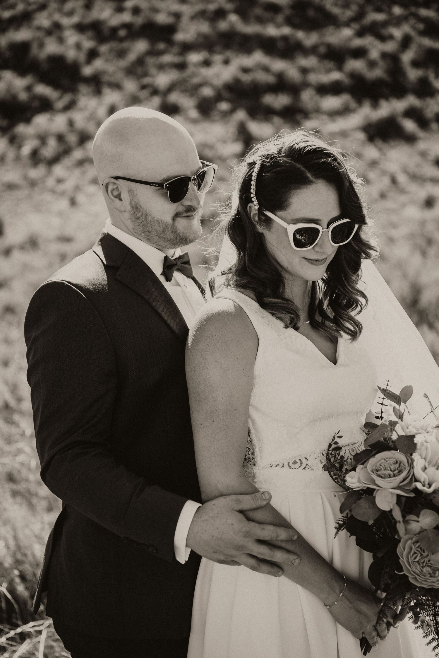Black and white photo of bride and groom standing in an embrace. Wedding photographer in the Okanagan