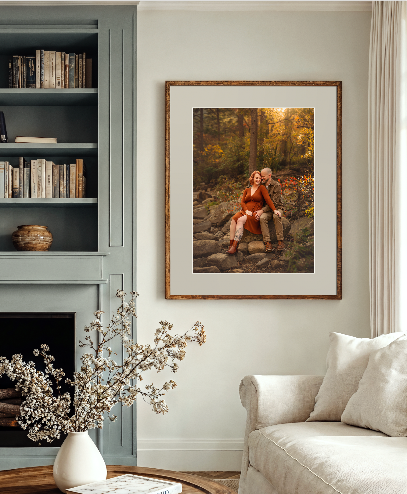 Framed autumn forest couple portrait in warm wood frame displayed above fireplace in elegant living room with built-in bookshelves.