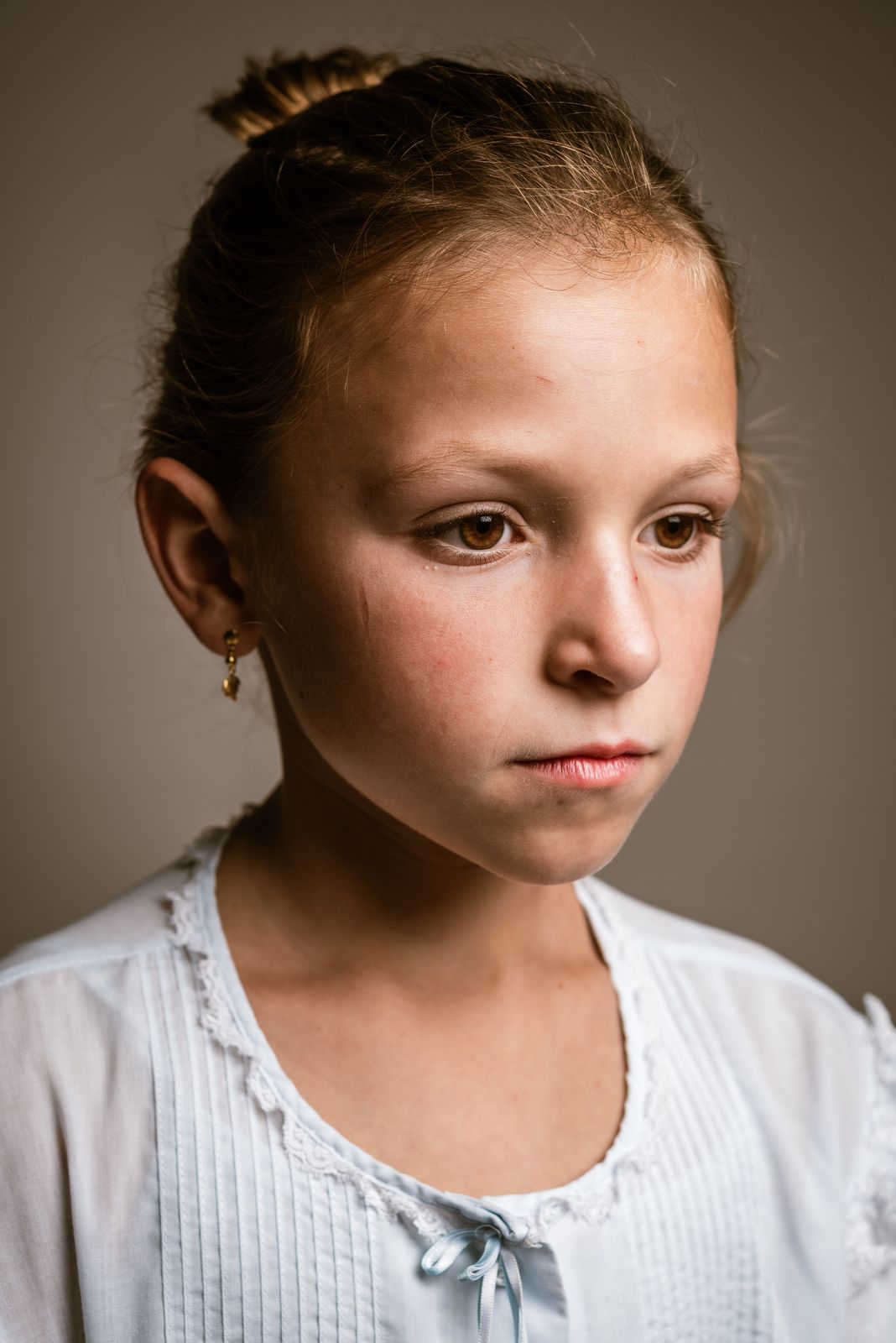 Klassiek portret van een kind in een witte blouse dat met een rustige blik opzij kijkt in de studio van Bart Boodts Photography in Hemiksem.