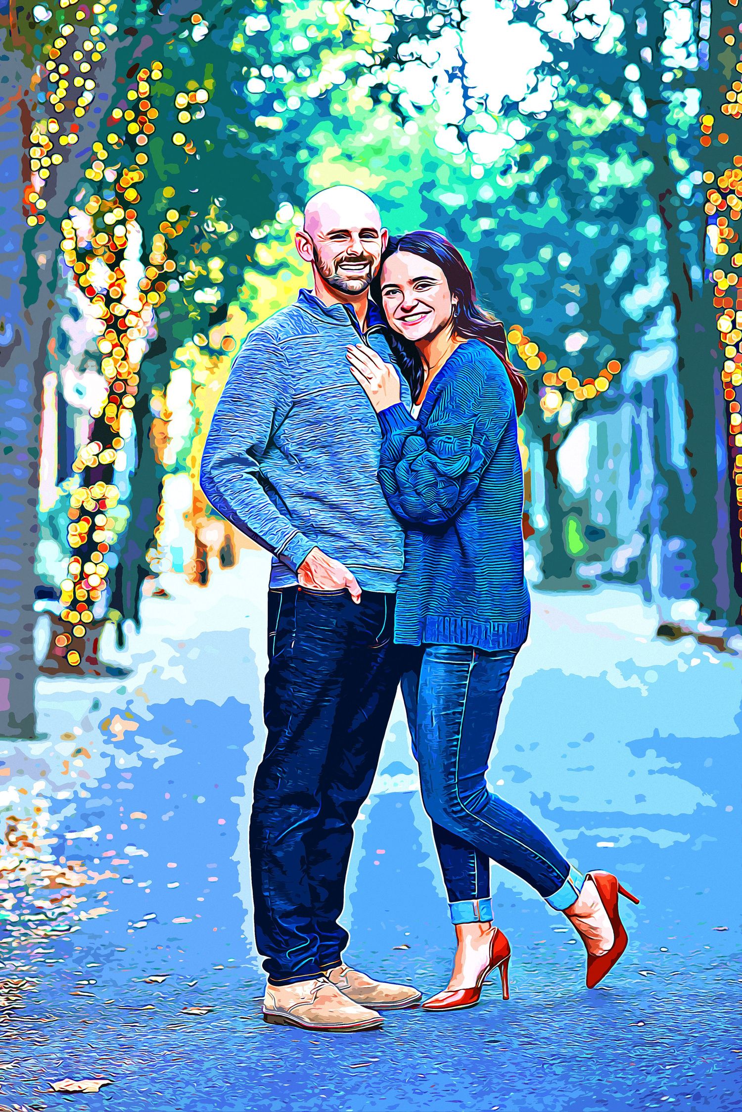 A smiling couple poses on a tree-lined path adorned with warm fairy lights, dressed in blue casual wear and red heels.