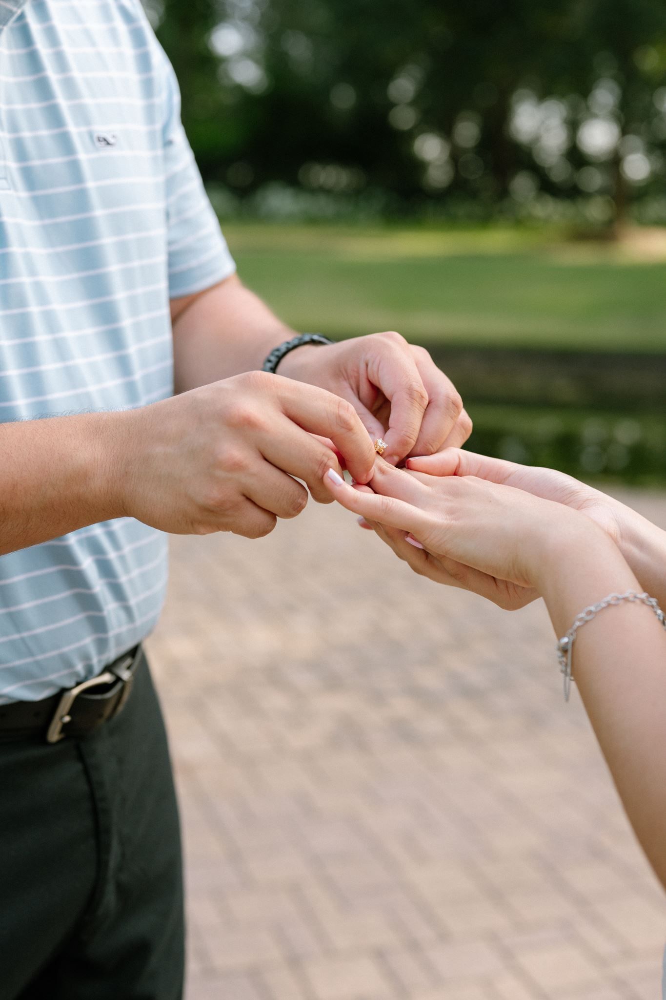 Man placing a ring on a woman's finger outdoors at park near The Woodlands Tx