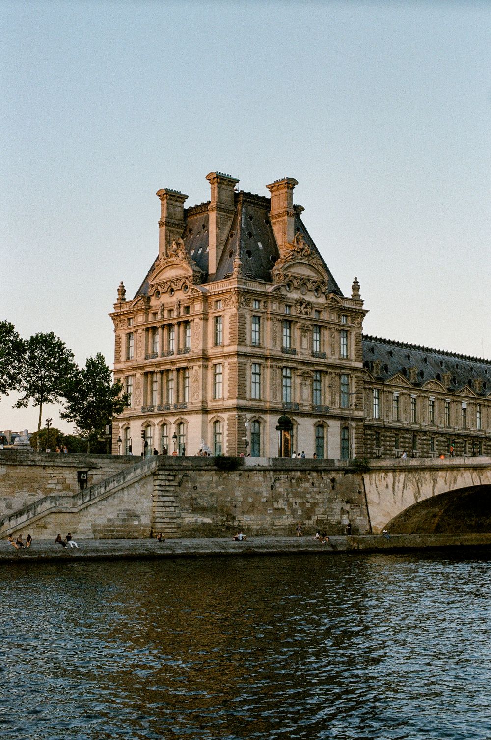 Historic Louvre Museum pavilion along the Seine River in Paris, France, at golden hour.