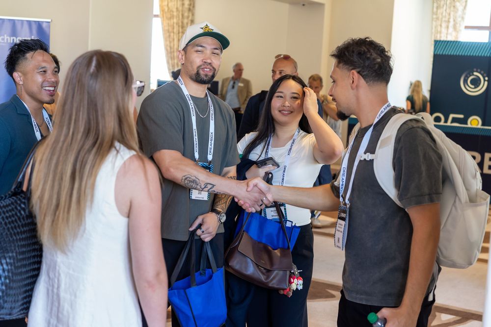 People networking and shaking hands at a professional conference event indoors.