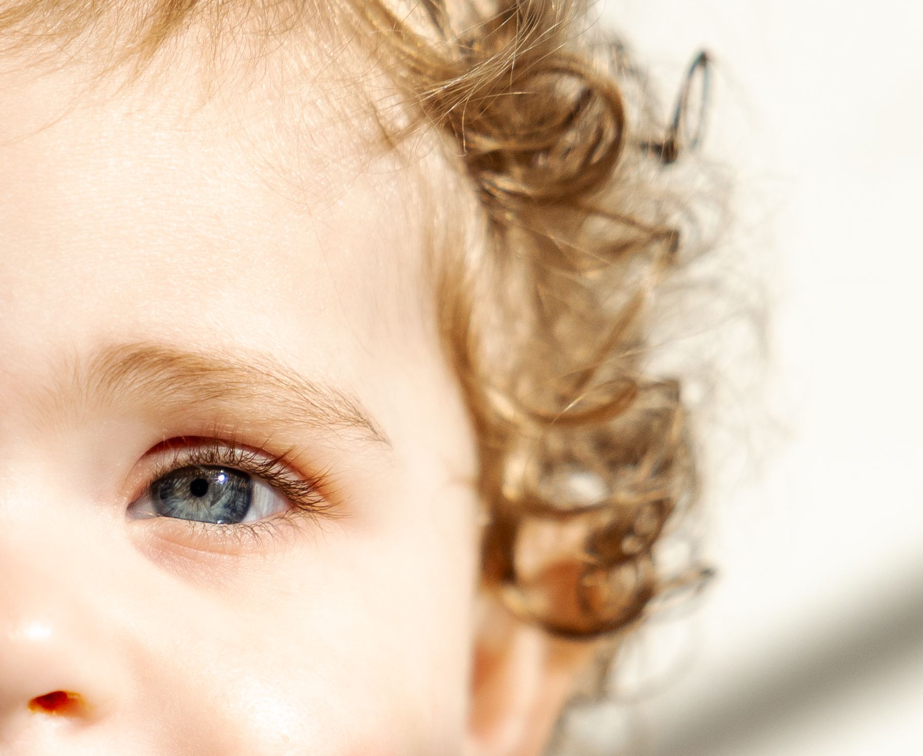 Close-up portrait of a young child with curly blonde hair and bright blue eyes.