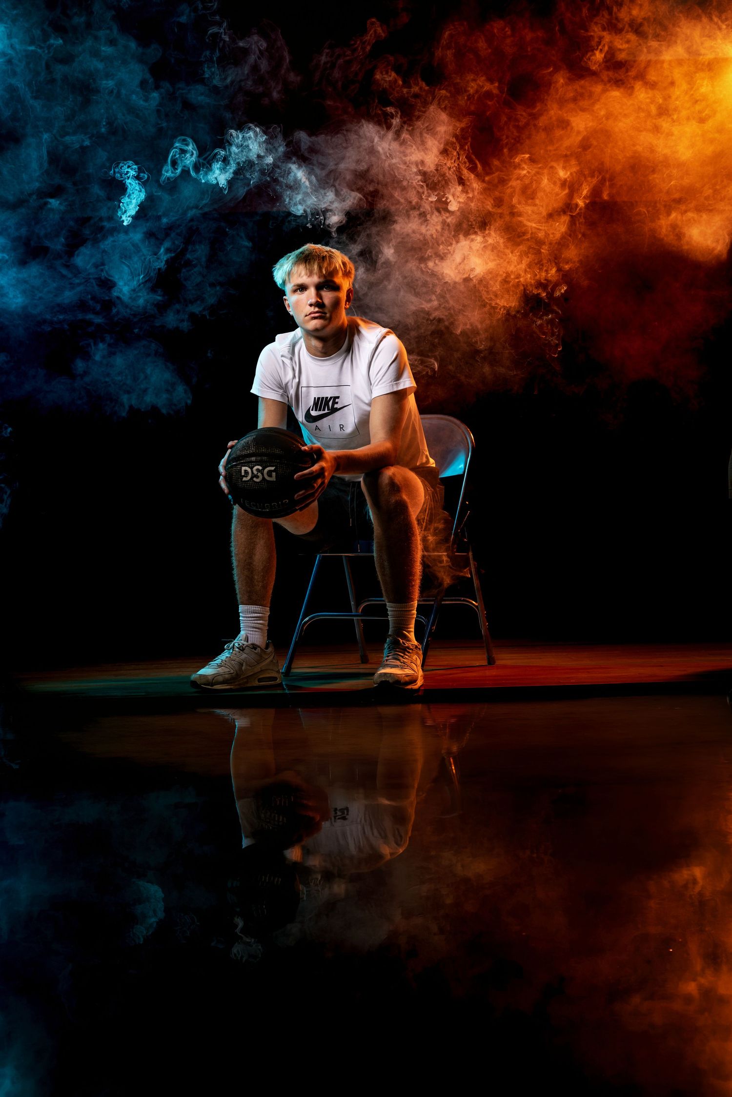 Dramatic senior sports portrait with blue and orange smoke and studio lighting
