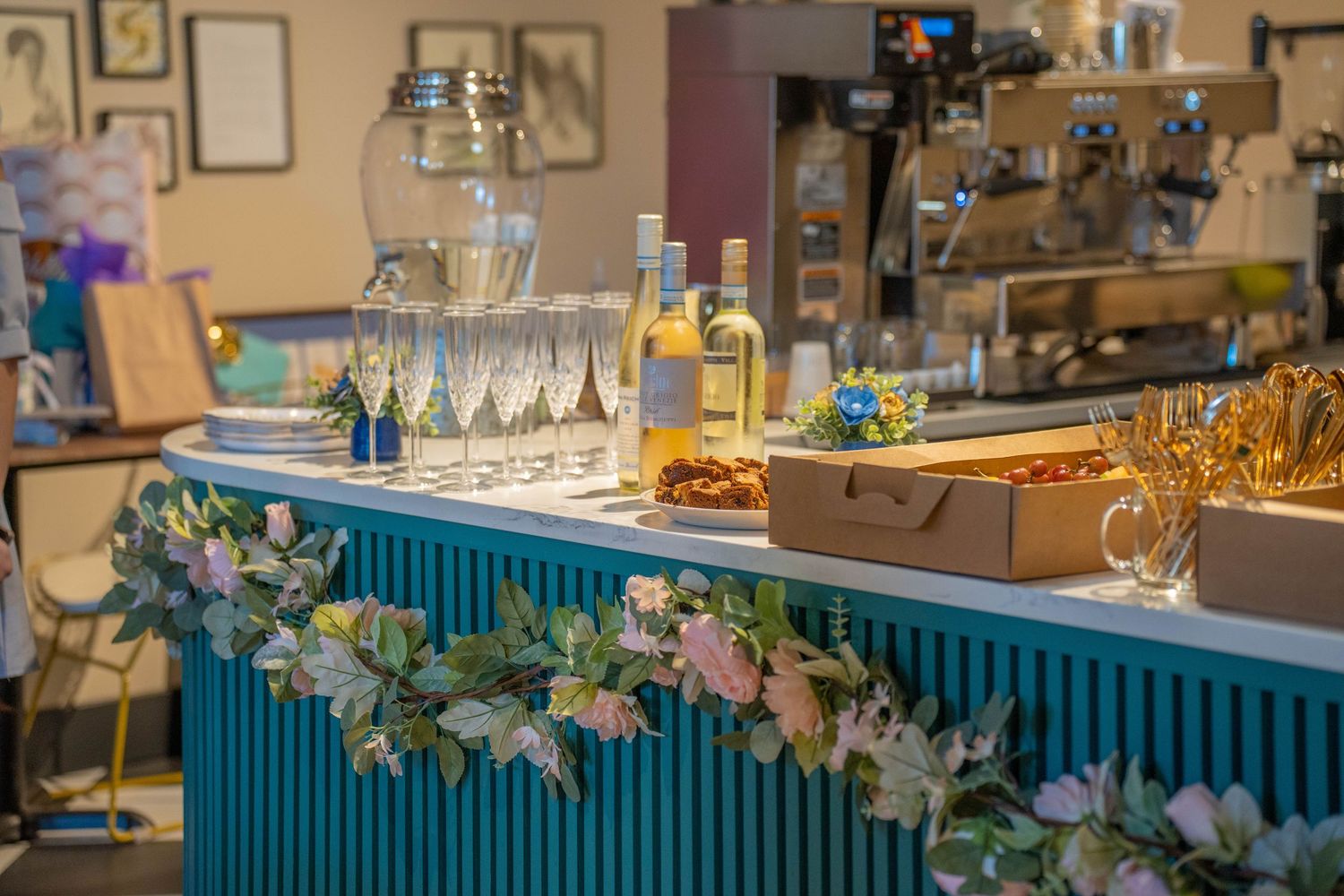 Elegant bar setup with champagne flutes, wine bottles, and floral garland decorations for a special event.
