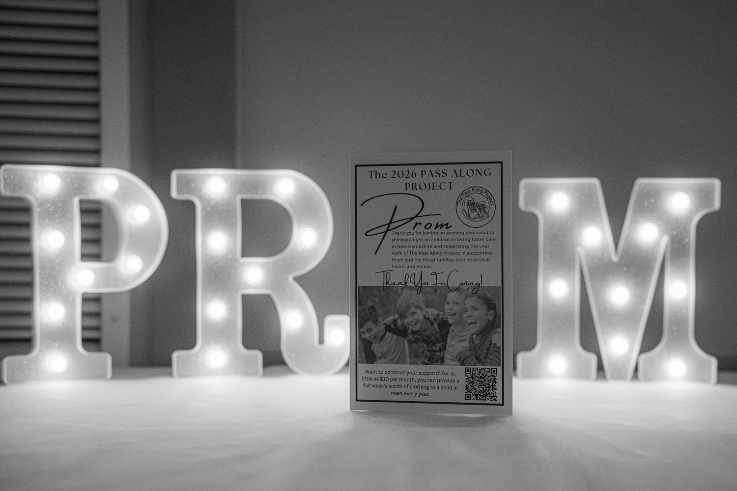 Black and white photo of illuminated PROM letter lights with a decorative sign displayed between them.