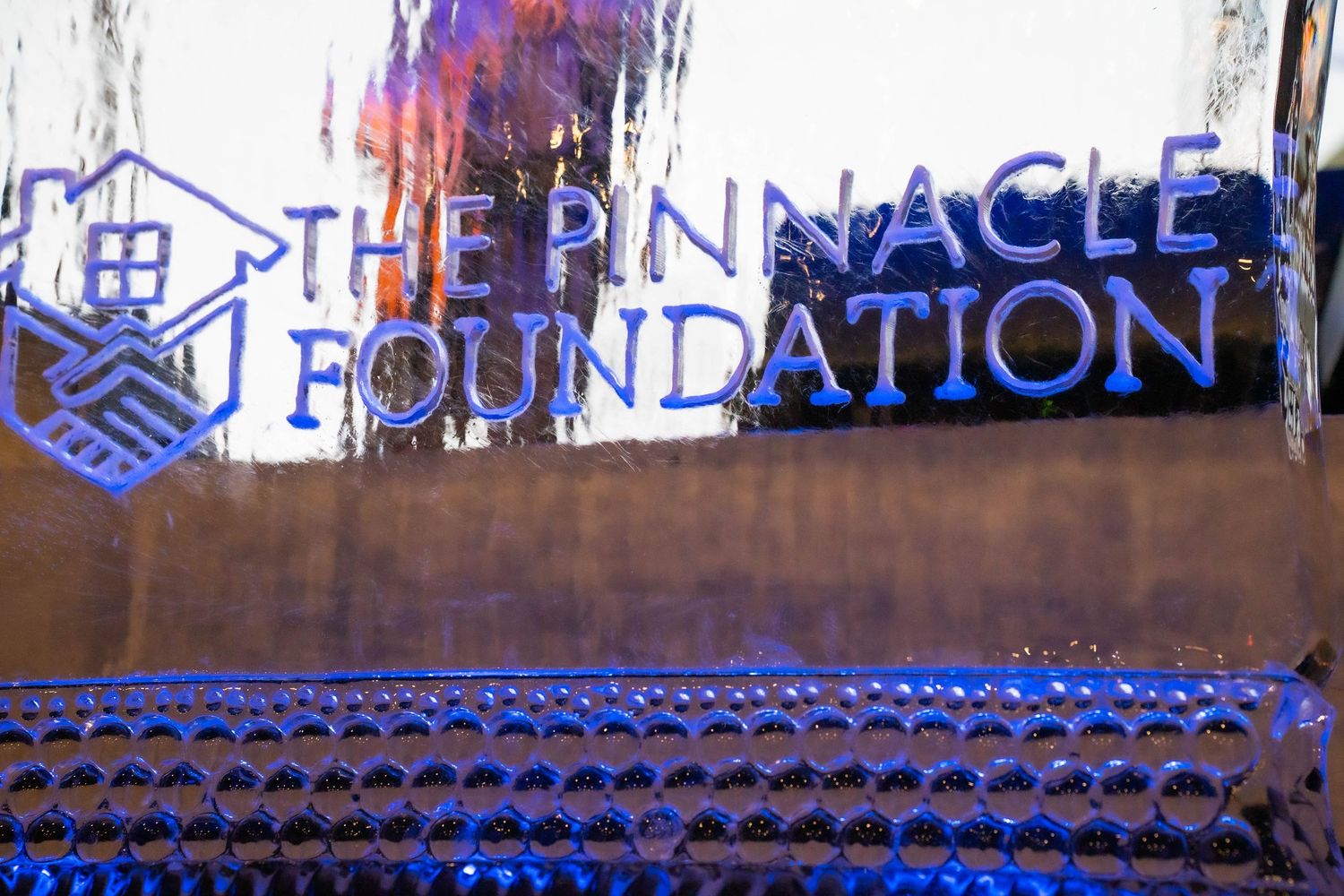 The Pinnacle Foundation illuminated sign displayed in blue neon lighting against a textured wall backdrop.