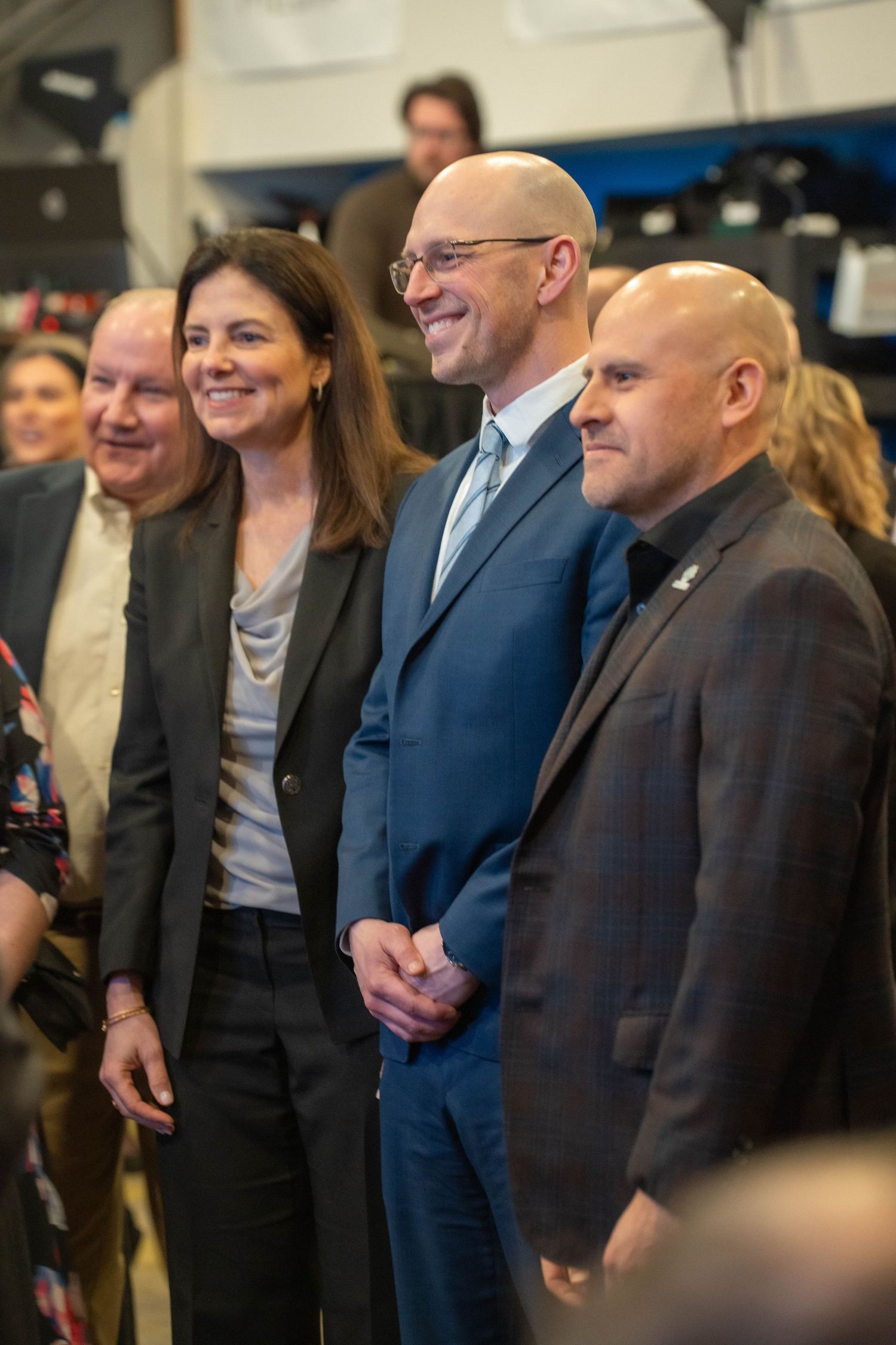Group of four professionals in business attire smiling at a formal indoor event.