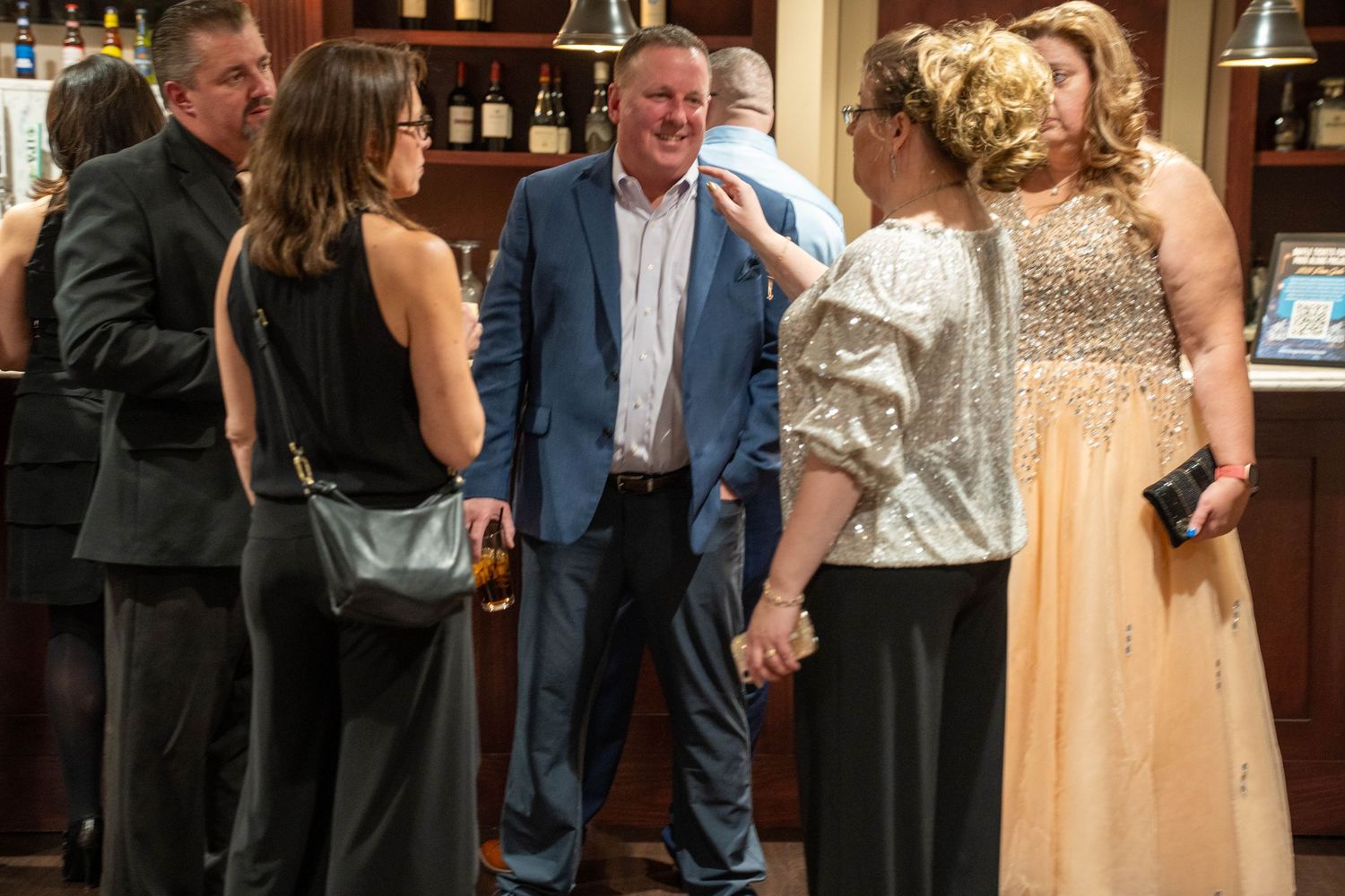 Group of elegantly dressed adults socializing at a bar during a formal evening event.
