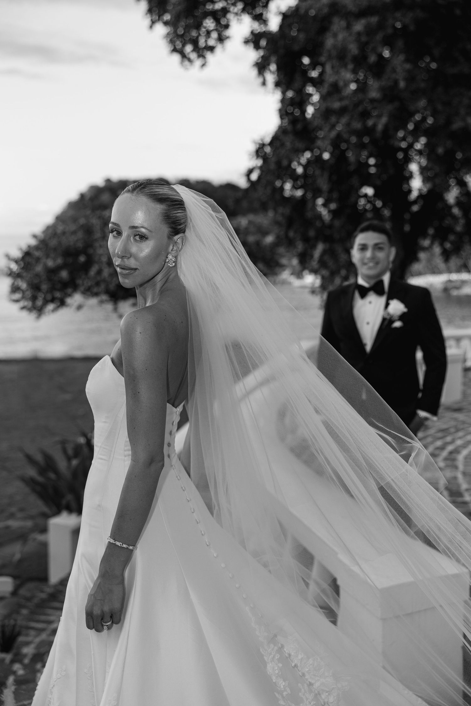 Black and white wedding photo of bride in flowing gown and veil looking back. Round Hill Hotel & Villas wedding. Luxury Caribbean wedding