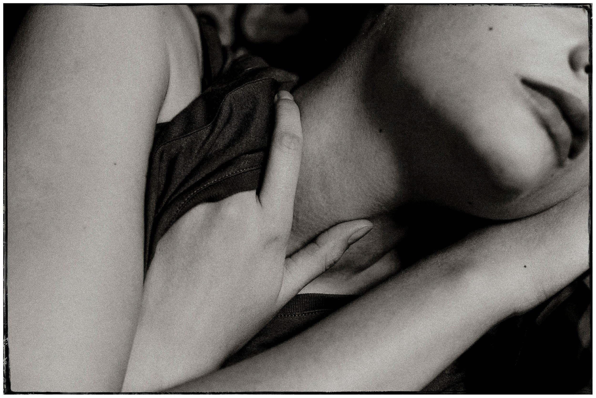 Black and white intimate photograph of a person resting with hand gently placed on chest.