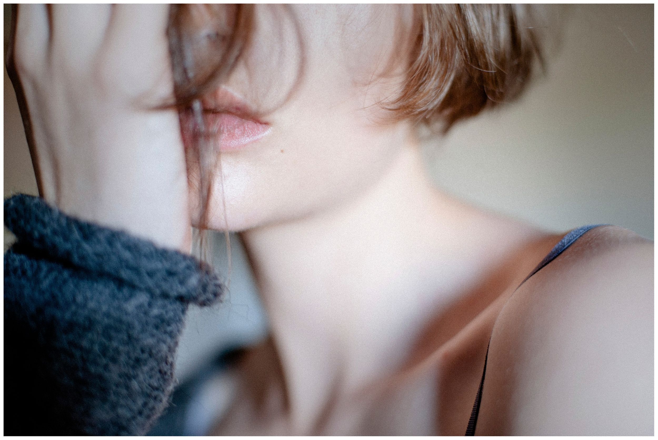 Close-up portrait of a young woman with short hair, soft skin, and subtle lips in natural light.