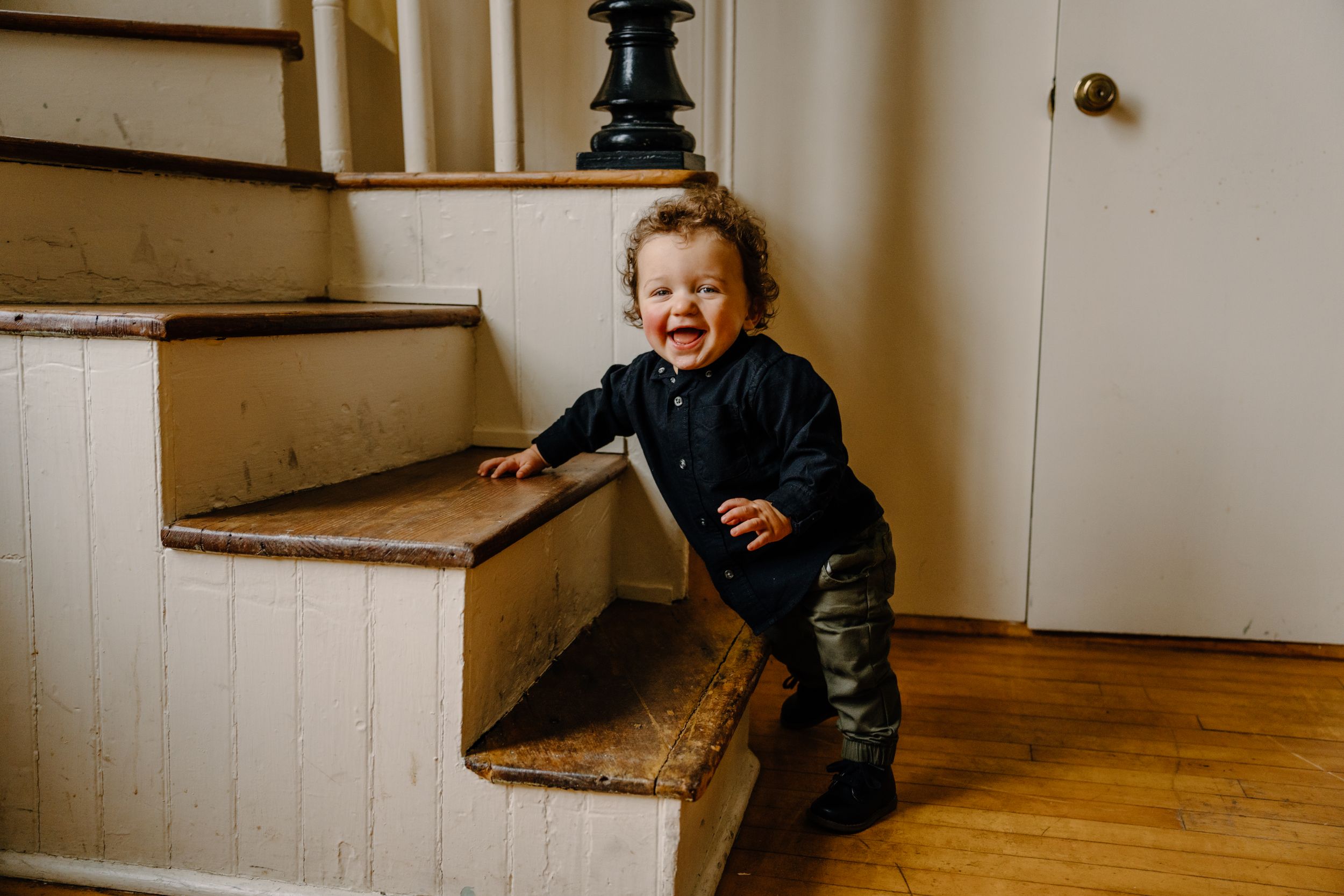A series of four photos showing a small child playfully crawling up wooden stairs.