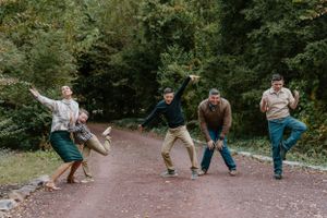 Group of people jumping and posing playfully on a forest path.