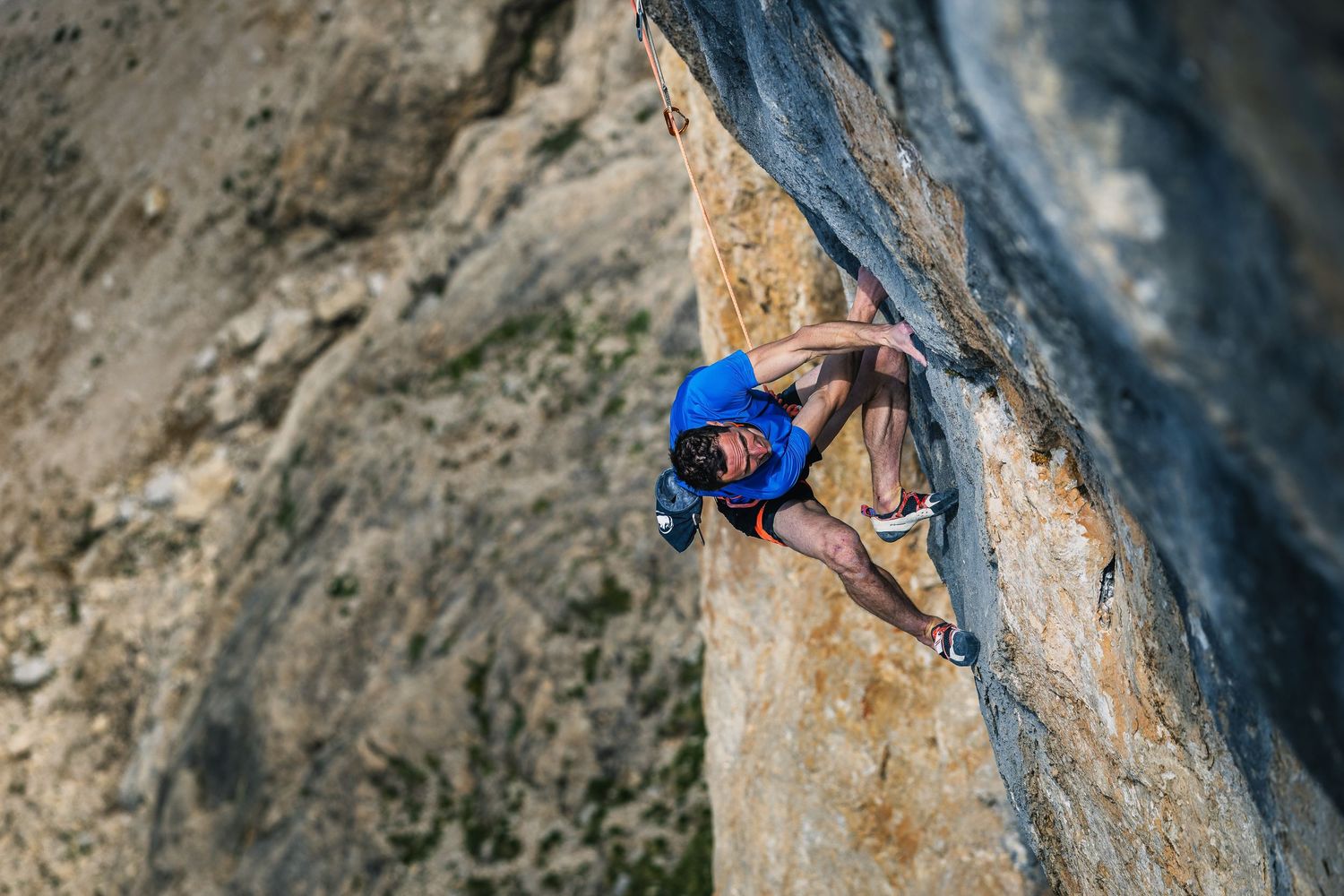 Adam Ondra in a blue top climbing the steep orange and grey limestone of Egoland, Marmolada South Face, Dolomites. Photo: Jan Virt
