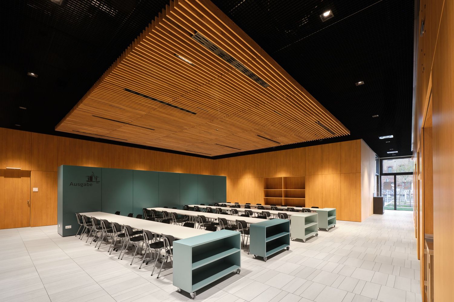 Modern meeting room with warm wood slat ceiling, long tables, gray chairs, teal storage shelves and wood paneled walls.