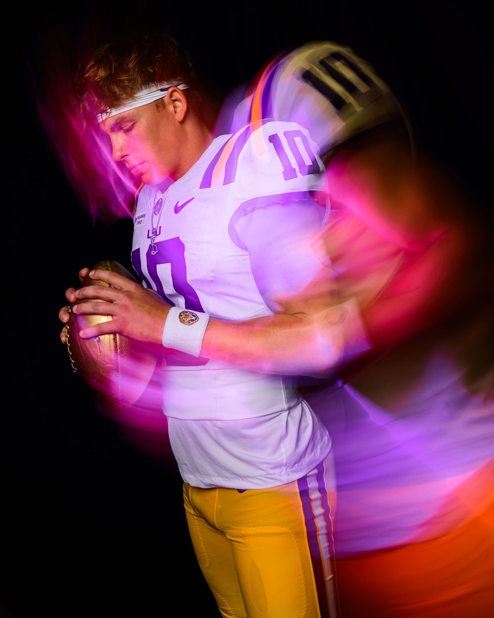 LSU Tigers quarterback in white #10 jersey poses with football, surrounded by colorful light painting effects on dark background.