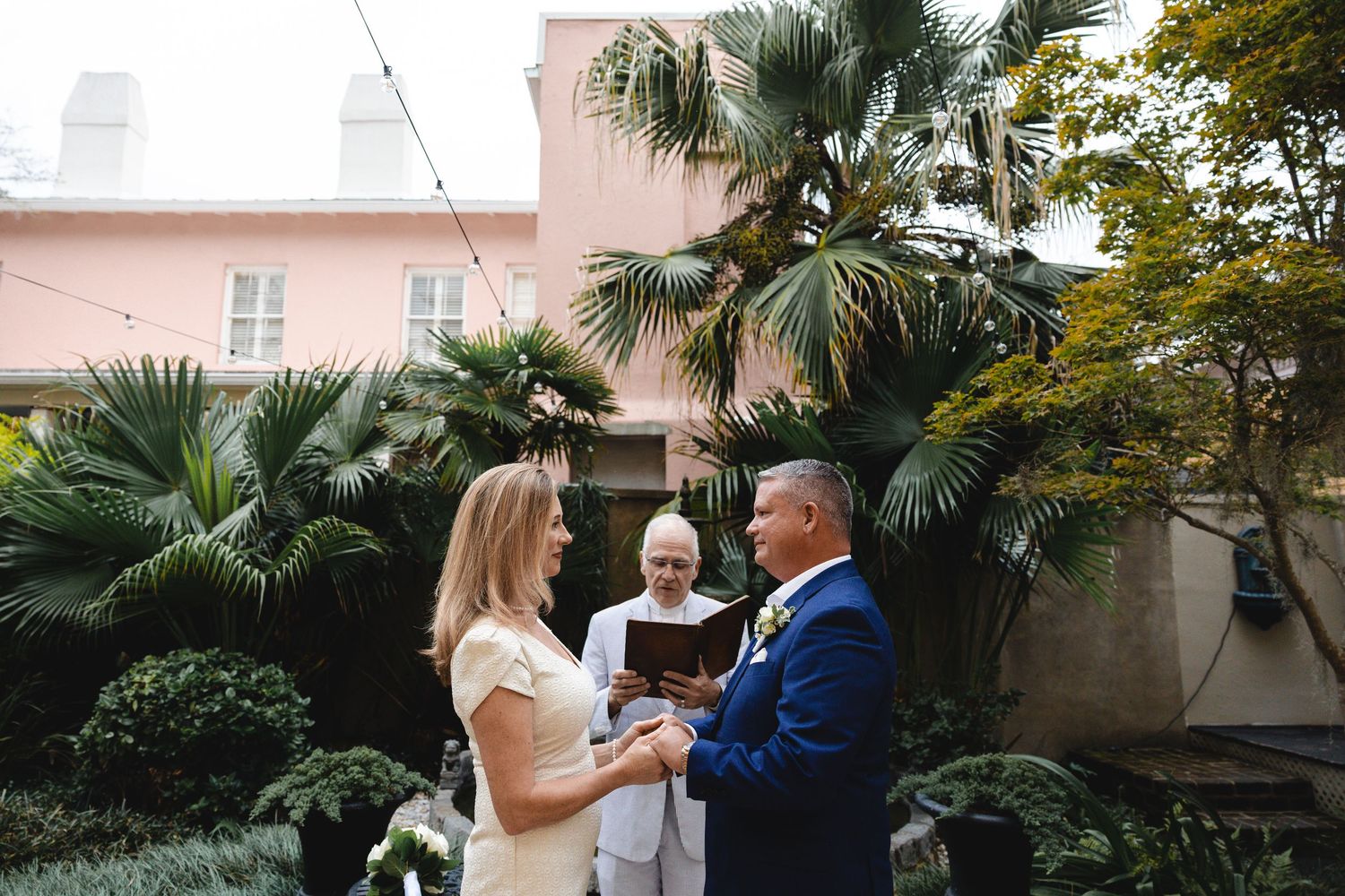 A couple exchanges vows in an intimate outdoor wedding ceremony in a Savannah, GA garden at Forsyth Park Inn.