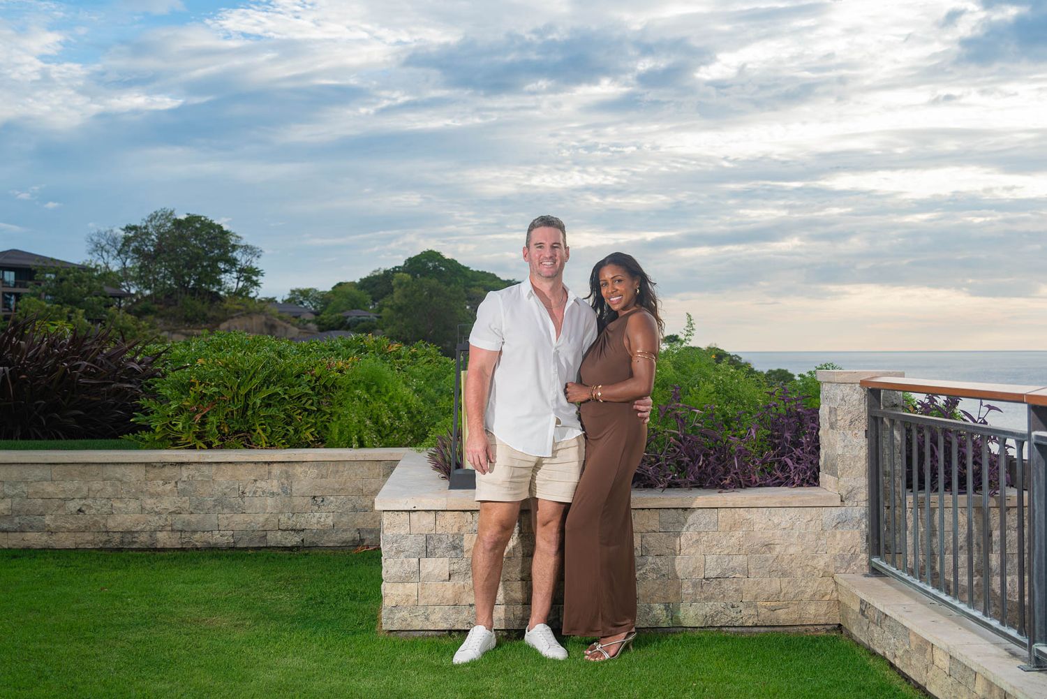 Couple posing together on a tropical terrace with lush greenery and ocean views at sunset at Nekajui, Ritz Carlton, Papagayo, Costa Rica