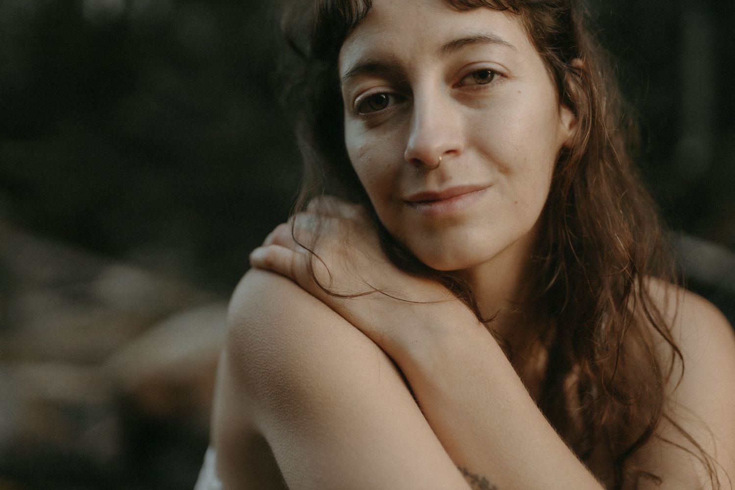 Self Love Session Photographer Heather Nolan smiles calmly on a softly lit riverbank