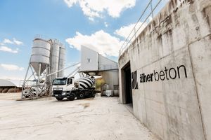 Zilher Beton concrete plant facility with mixer truck and industrial silos under a bright blue sky.