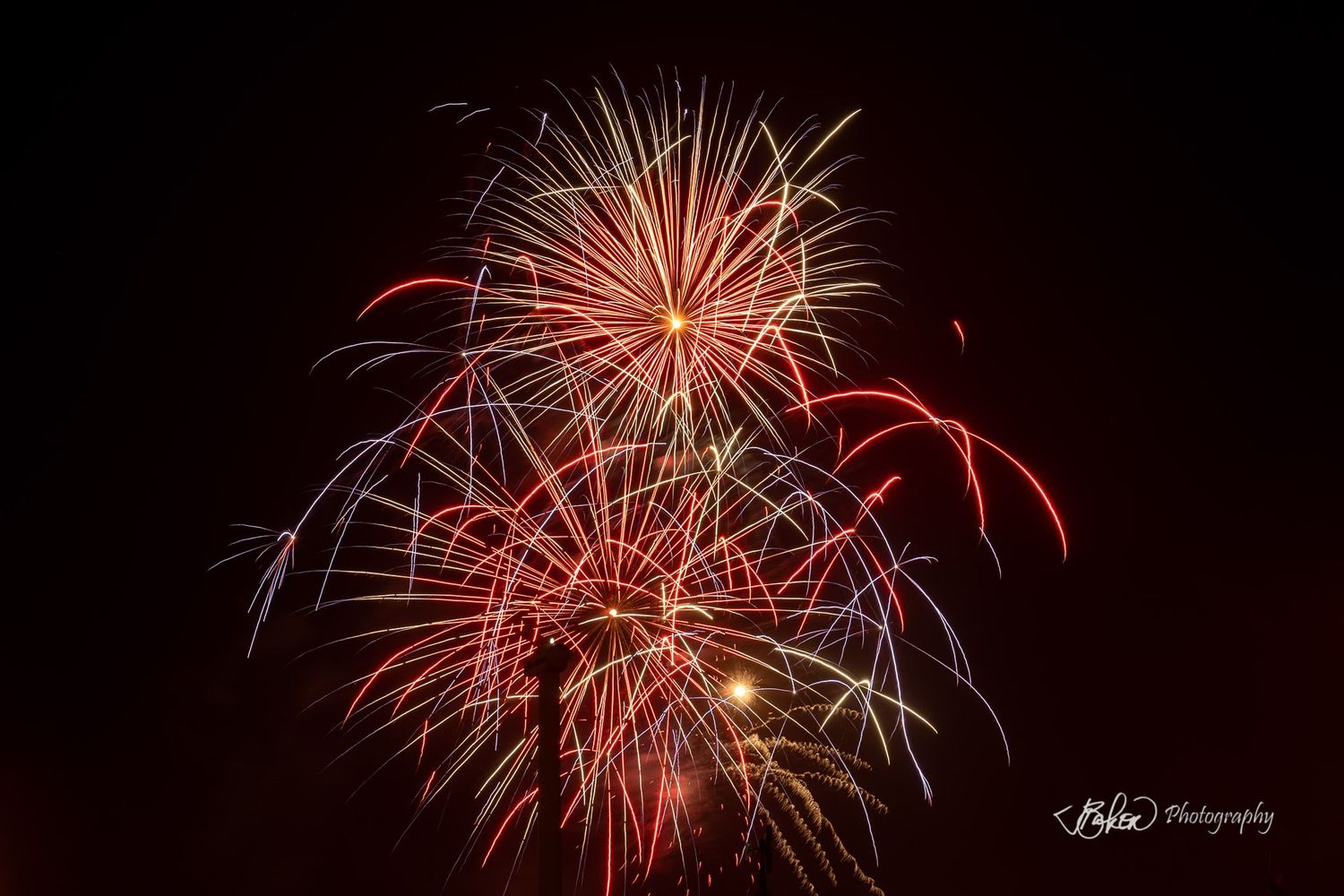 Vibrant red and gold fireworks exploding against a dark night sky in a stunning multi-burst display.
