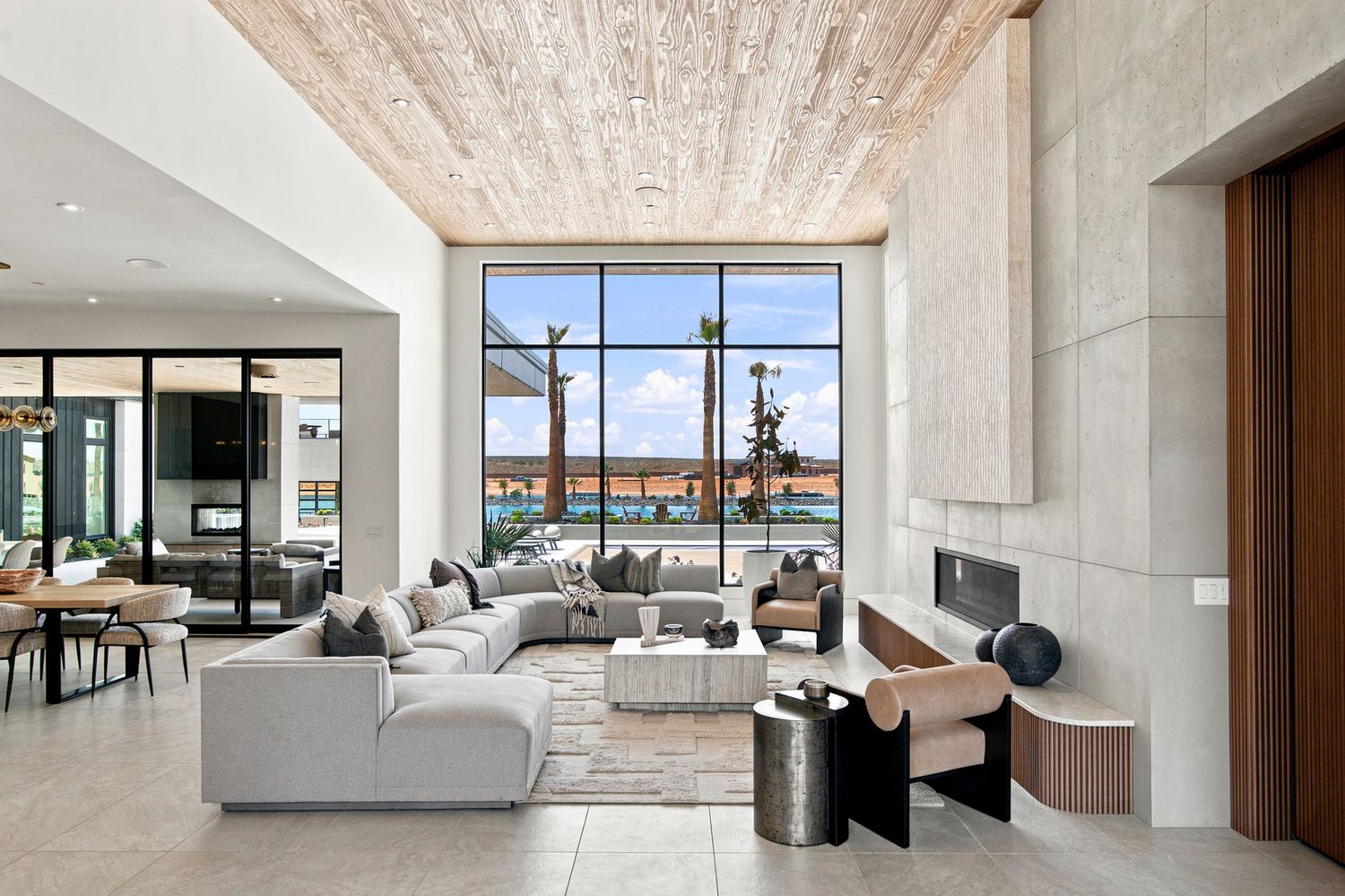 Bright open-concept living room and kitchen with a wood ceiling detail, sectional sofa, and floor-to-ceiling windows
