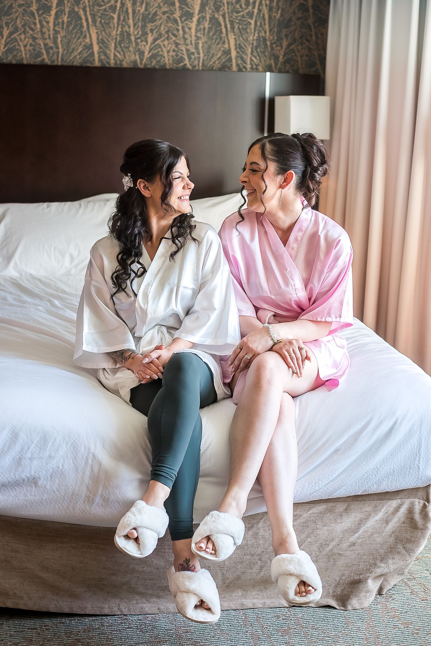 Bride and bridesmaid enjoying a candid moment while getting ready.